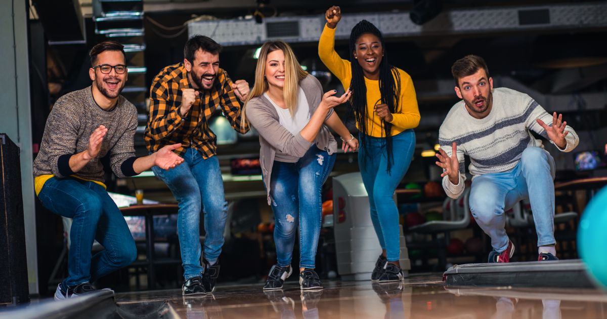 Group of friends enjoying time together laughing and cheering while bowling at club | Bowling Party